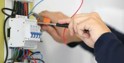 Electrician installing and adjusting circuit breakers in an electrical panel in Cambridge, MA