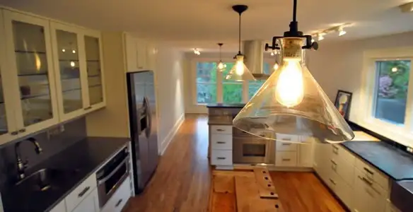 Residential electrician installing modern indoor light fixture in a home in Cambridge, MA
