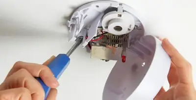 Certified technician wiring smoke detector during installation in Cambridge, MA